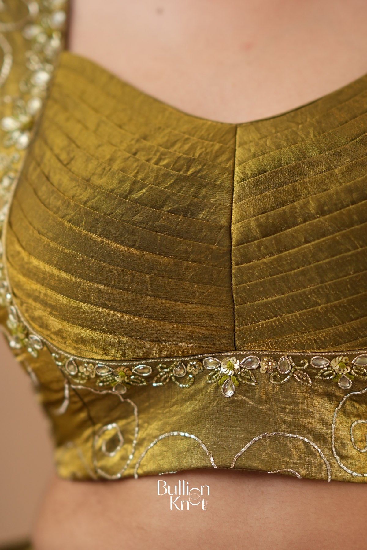 Close-up of a green saree with intricate patterns and embellishments.