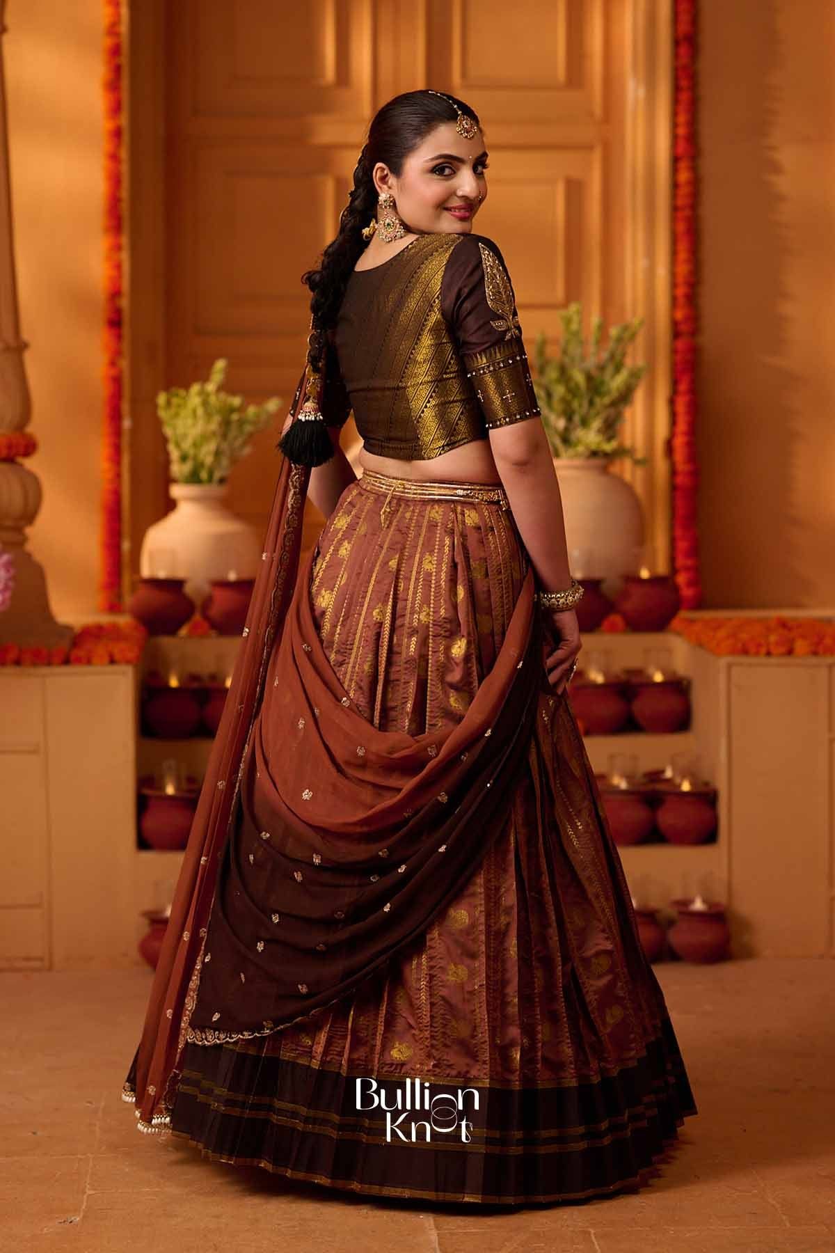 Elegant traditional lehenga set with gold brocade and copper brown pleated skirt, paired with a matching blouse, ornate jewelry, and styled for celebrations