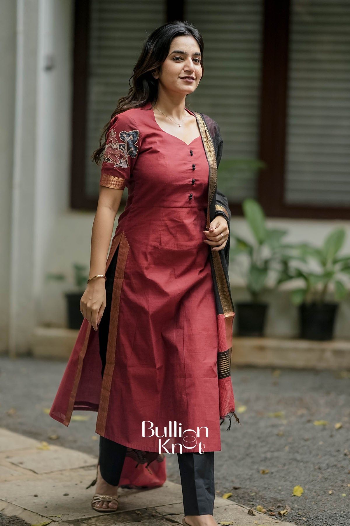 Close-up of maroon kurta with black buttons and embroidered sleeve details
