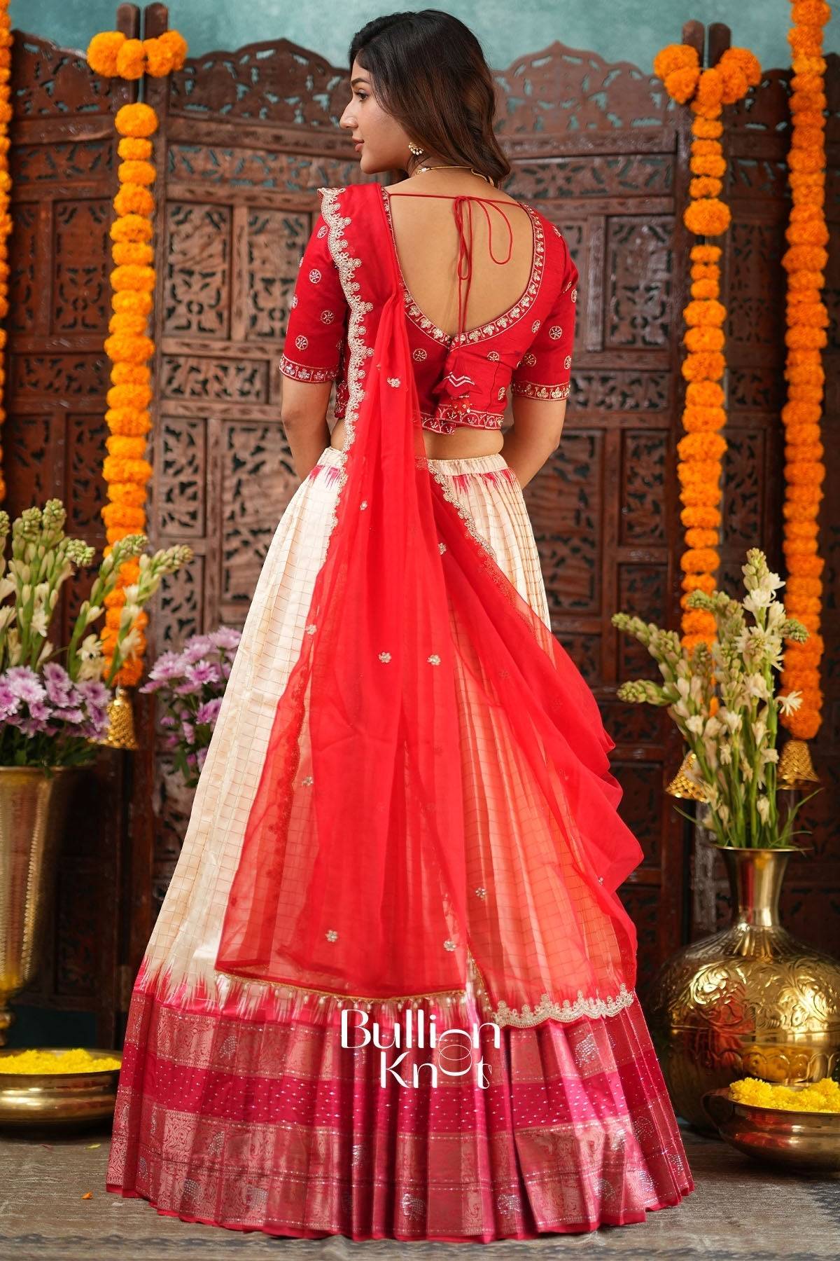 Woman in red traditional lehenga with blouse and dupatta, decorated with gold embroidery, at festive celebration