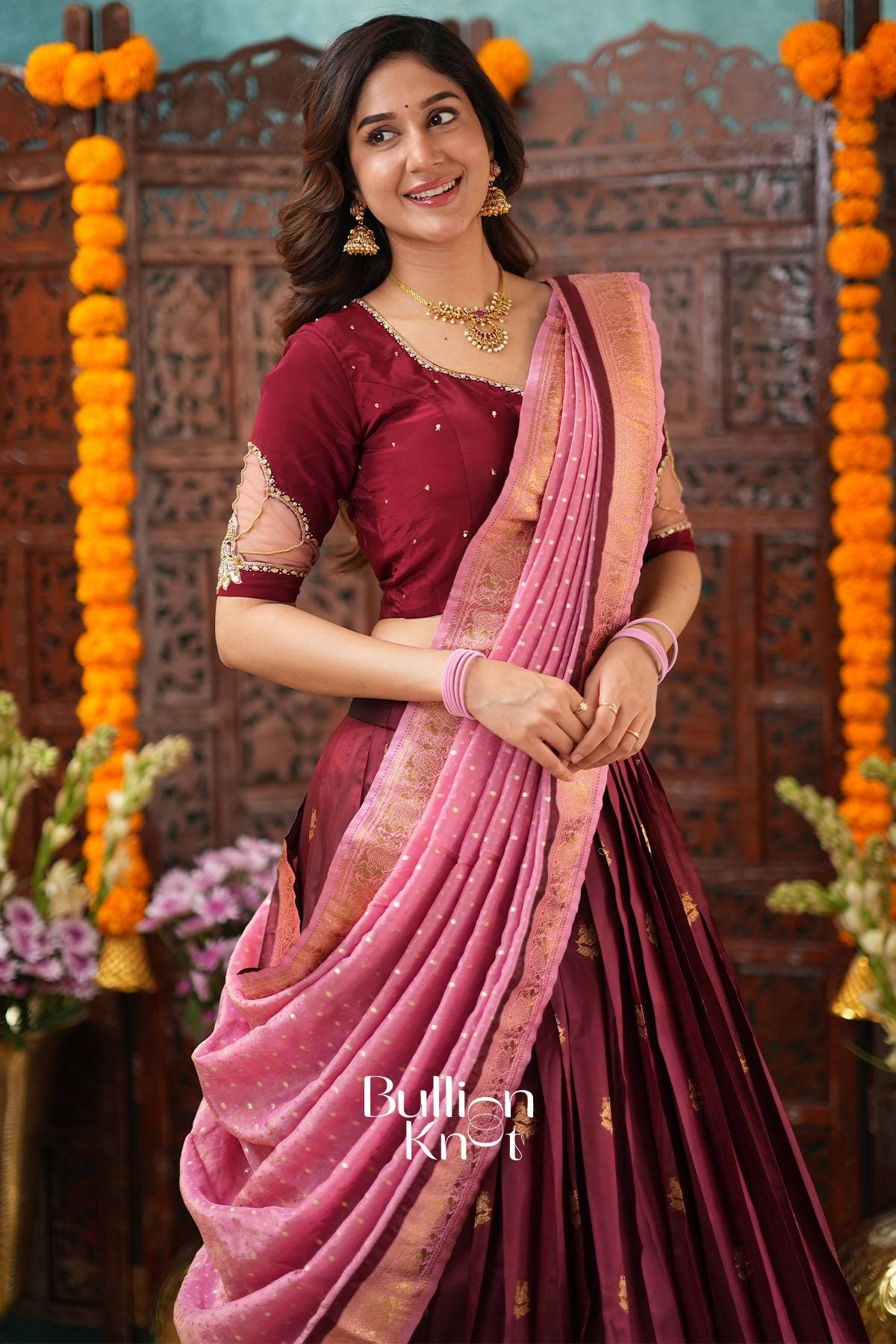 Elegant woman in maroon and pink Banarasi lehenga with floral background