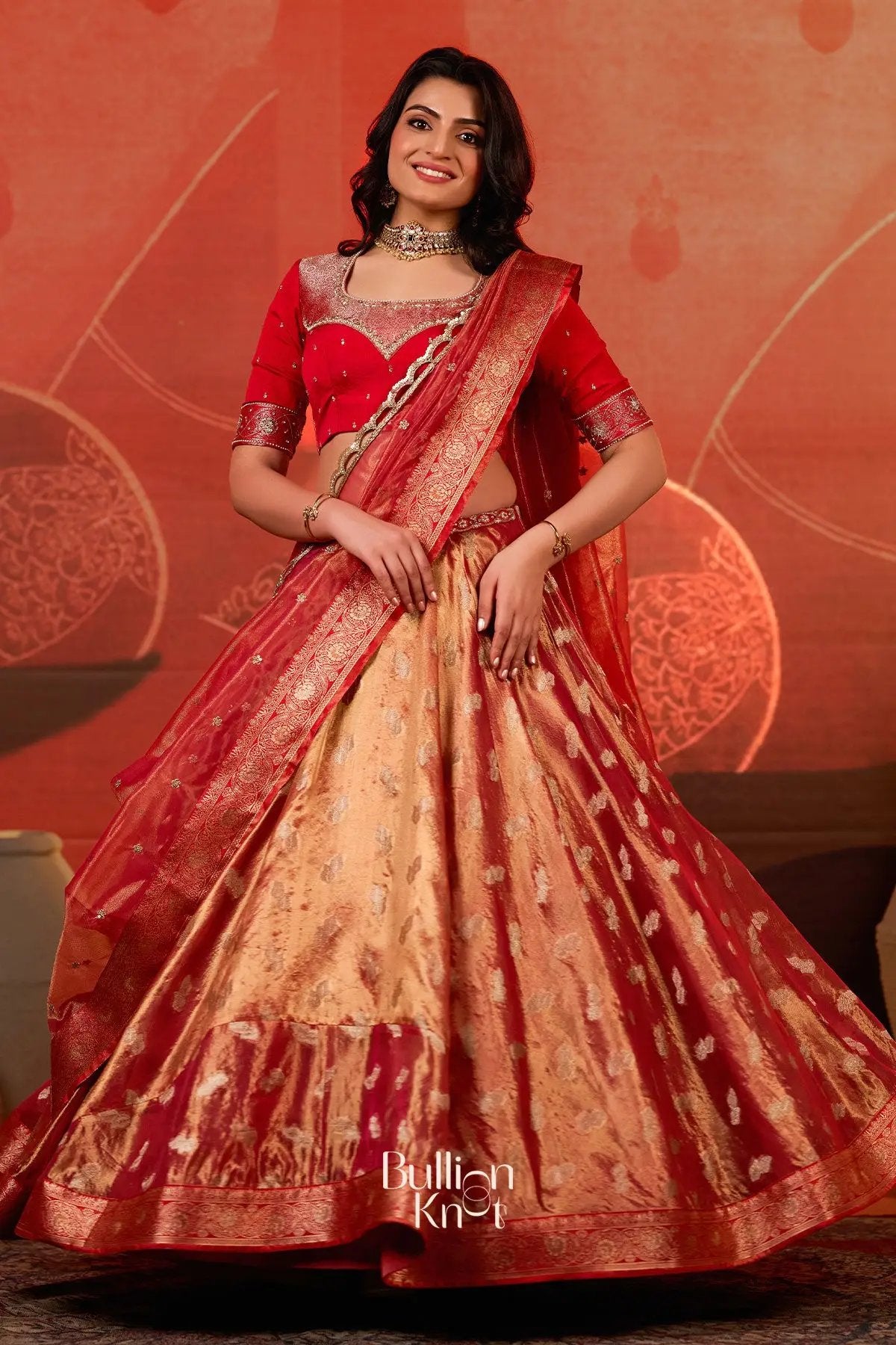 Front view of Exclusive Lehenga - Amulya Tissue Zari Lehenga Set in Red at bullionknot, displaying the vibrant red blouse and gold woven lehenga skirt.