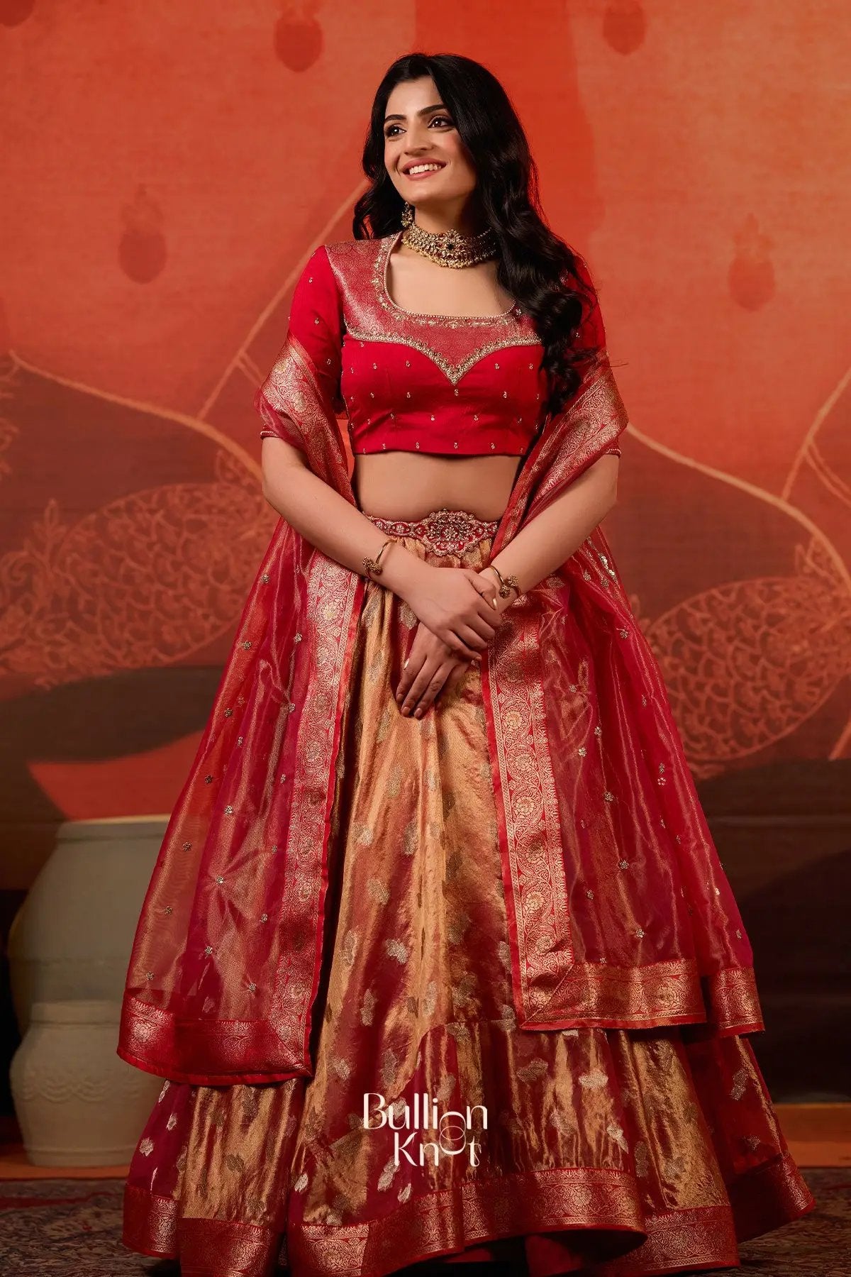 Model wearing Exclusive Lehenga - Amulya Tissue Zari Lehenga Set in Red at bullionknot, showcasing traditional red and gold Banarasi half saree design.