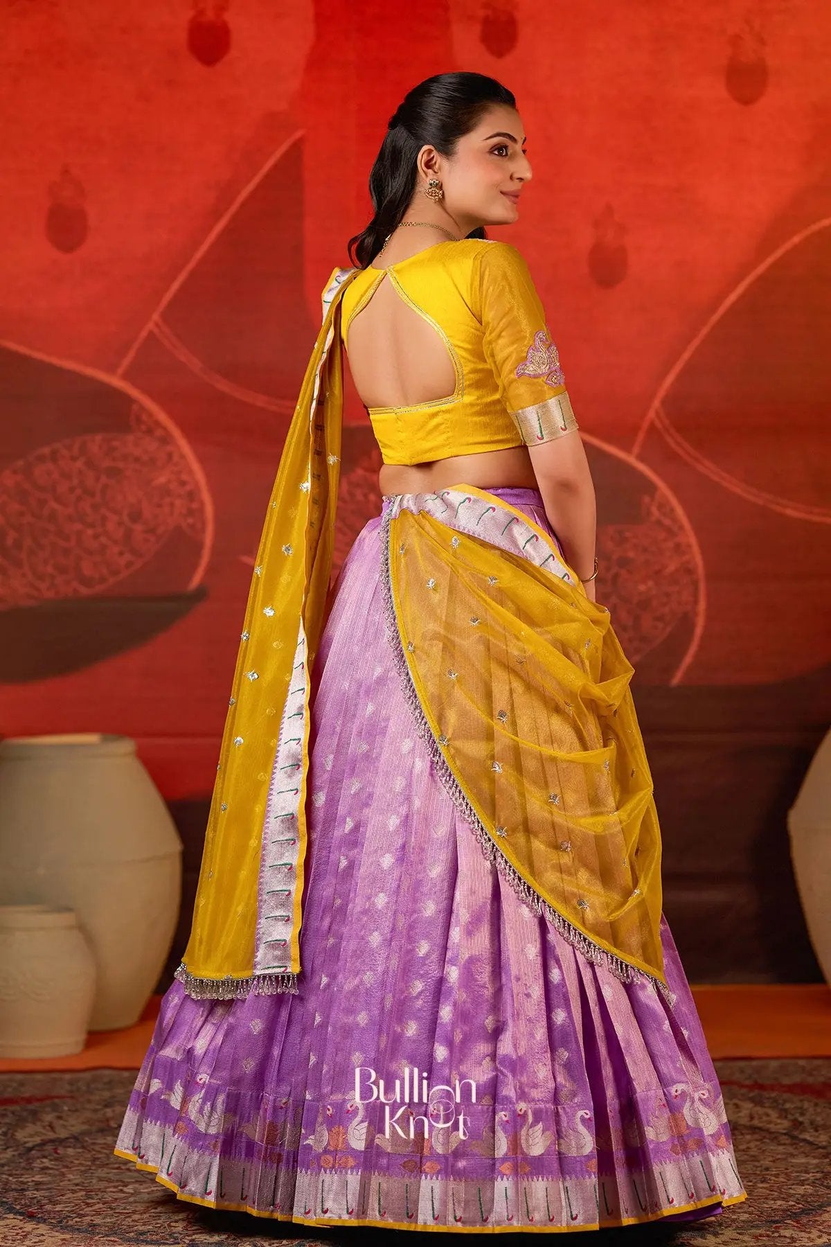 Back view of Kumudini Kota Lehenga Set in Lavender at bullionknot highlighting open-back blouse and sheer yellow dupatta with silver embellishments.