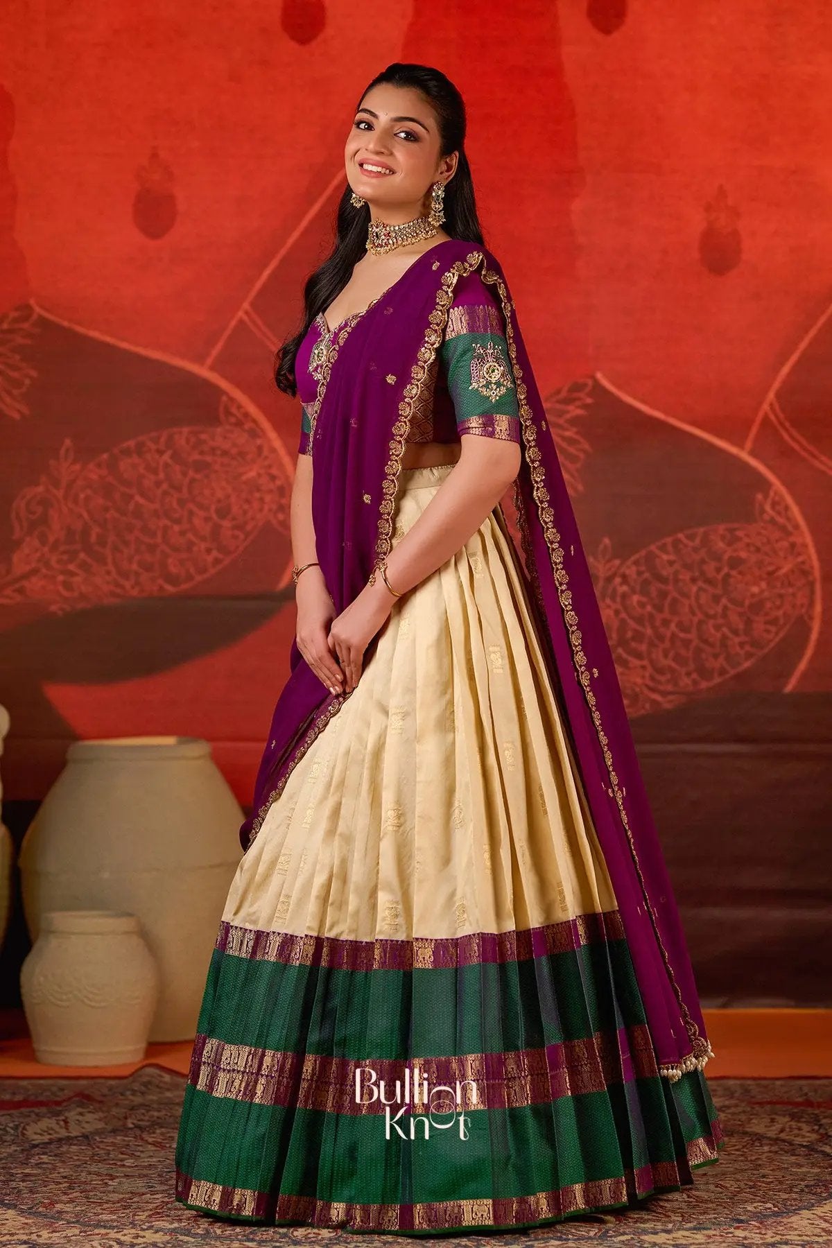 Front view of Exclusive Lehenga - Vishakha Half Saree in Vanilla at bullionknot, featuring a traditional vanilla skirt with green and purple woven borders.