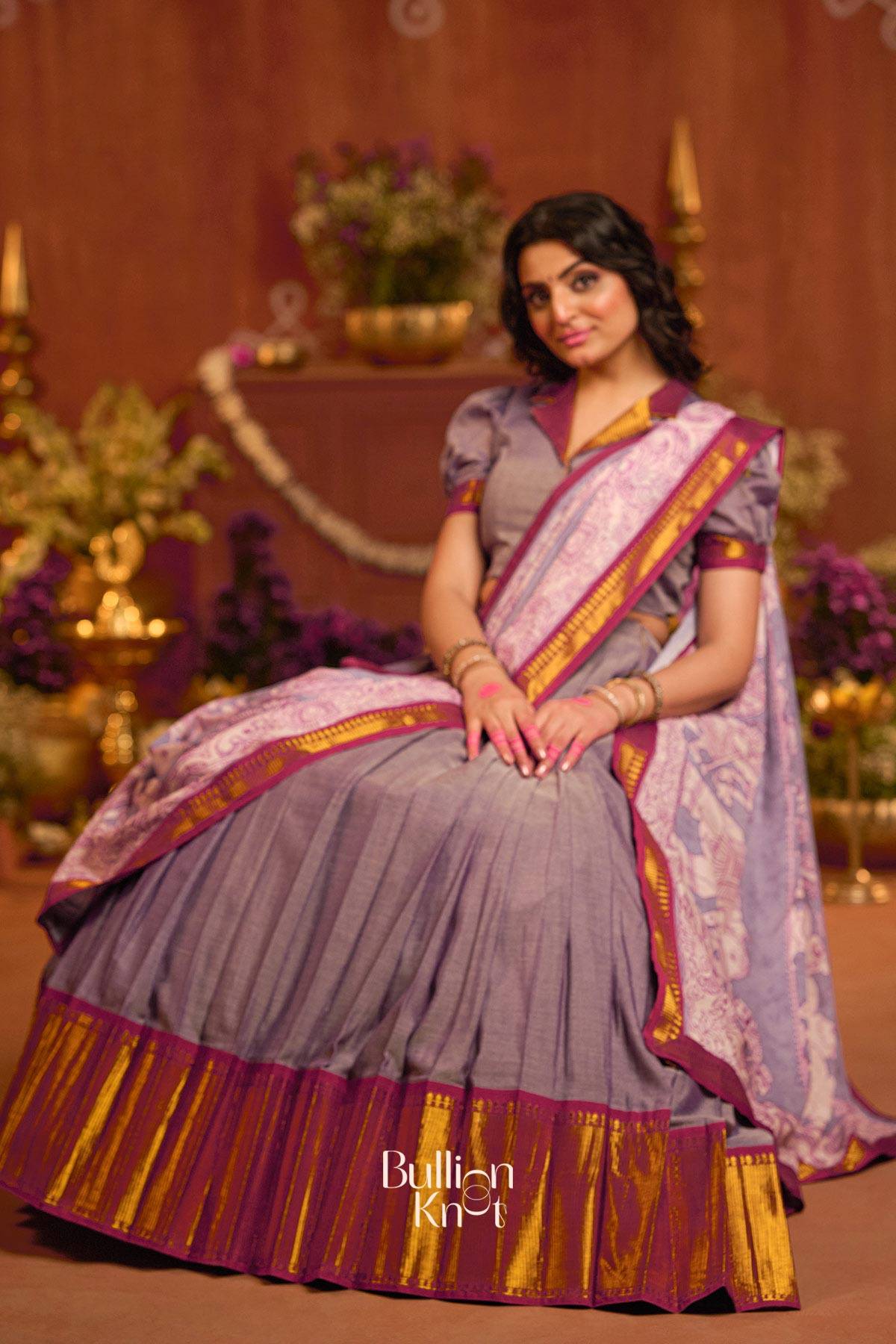 Seated pose of model in Gunika Lehenga Set in Lavender at bullionknot, showcasing full flare and vibrant zari hemline for ethnic charm.