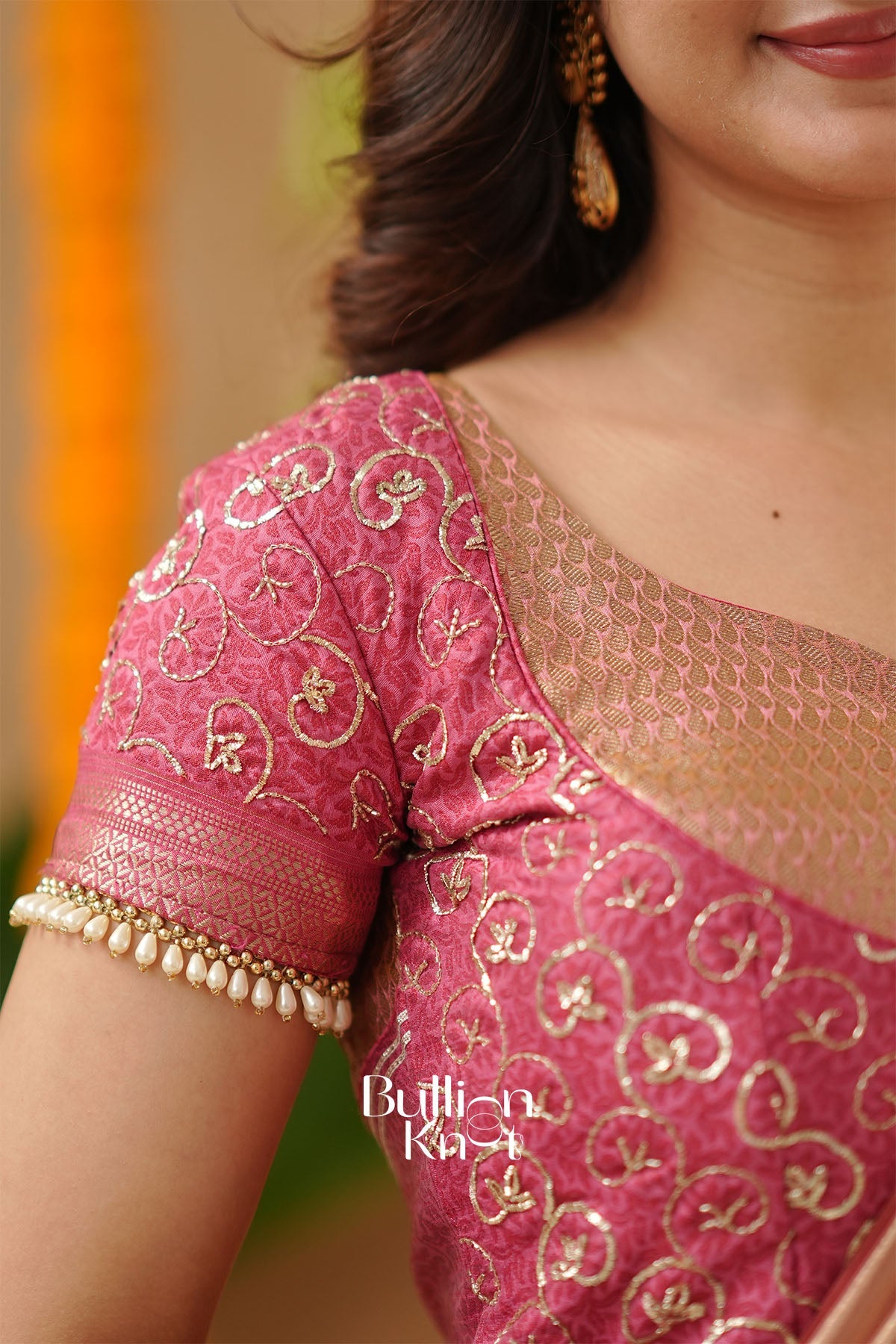 Close-up of a pink saree with gold embroidery and a blurred background