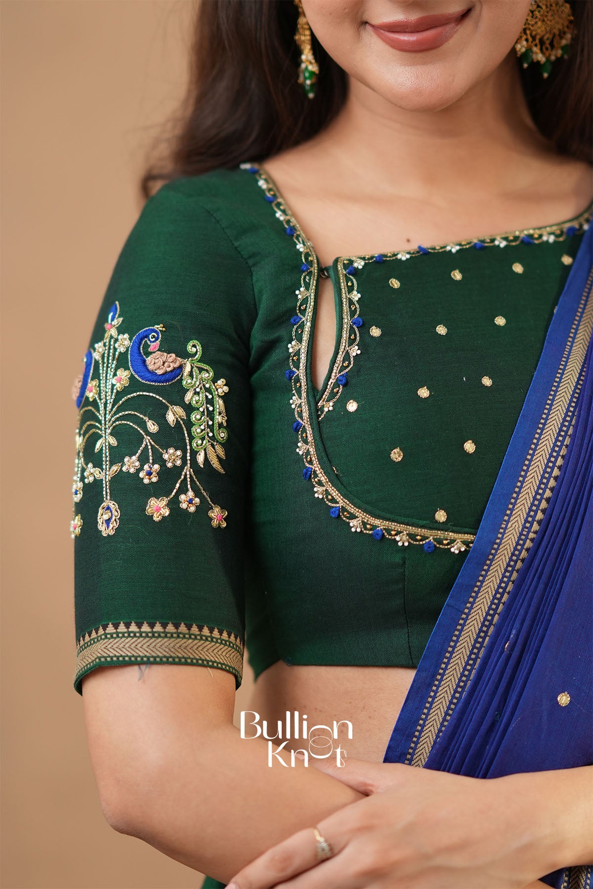 Green embroidered blouse with blue saree on a beige background