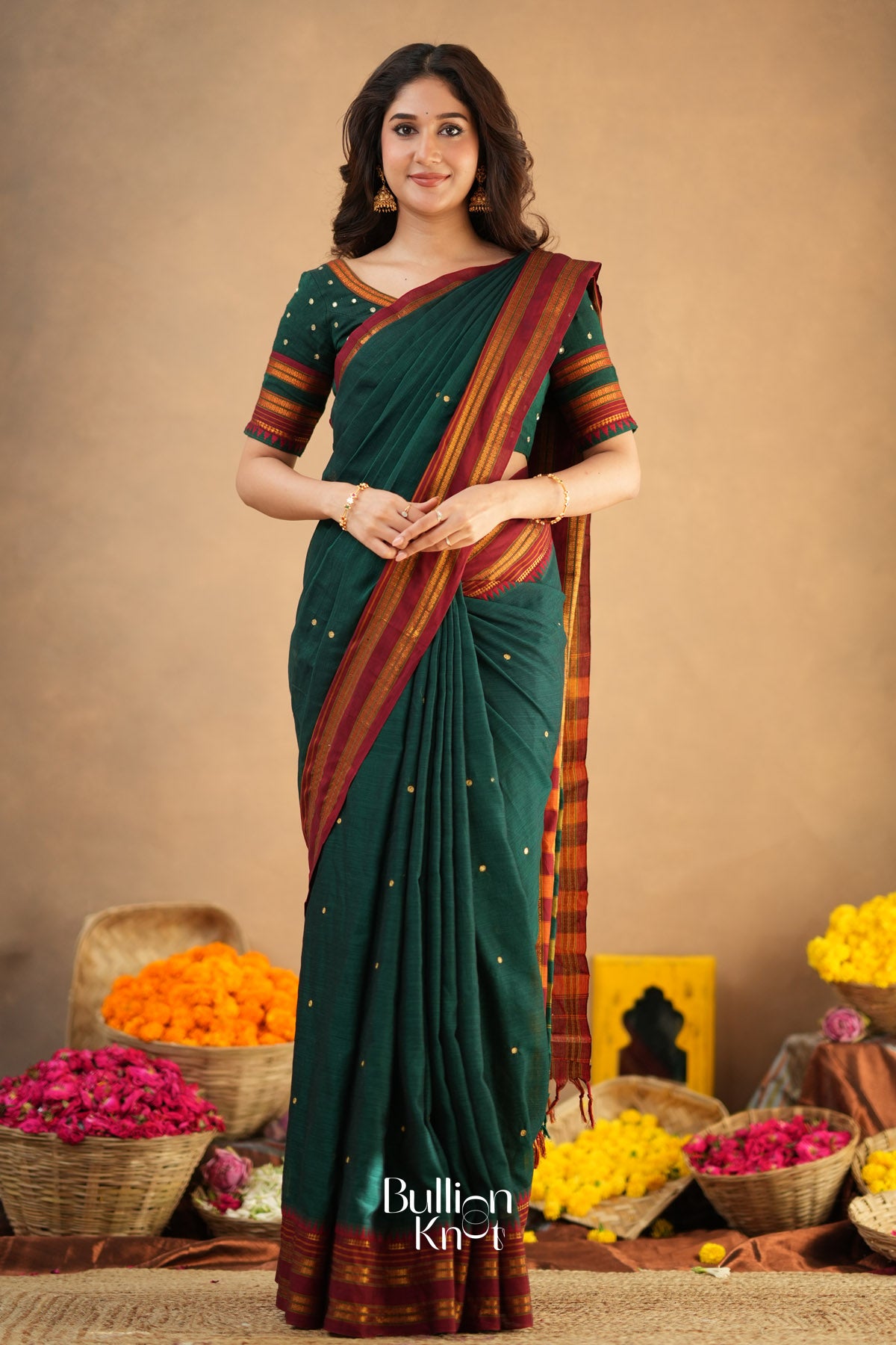 Woman wearing a green saree with a brown border