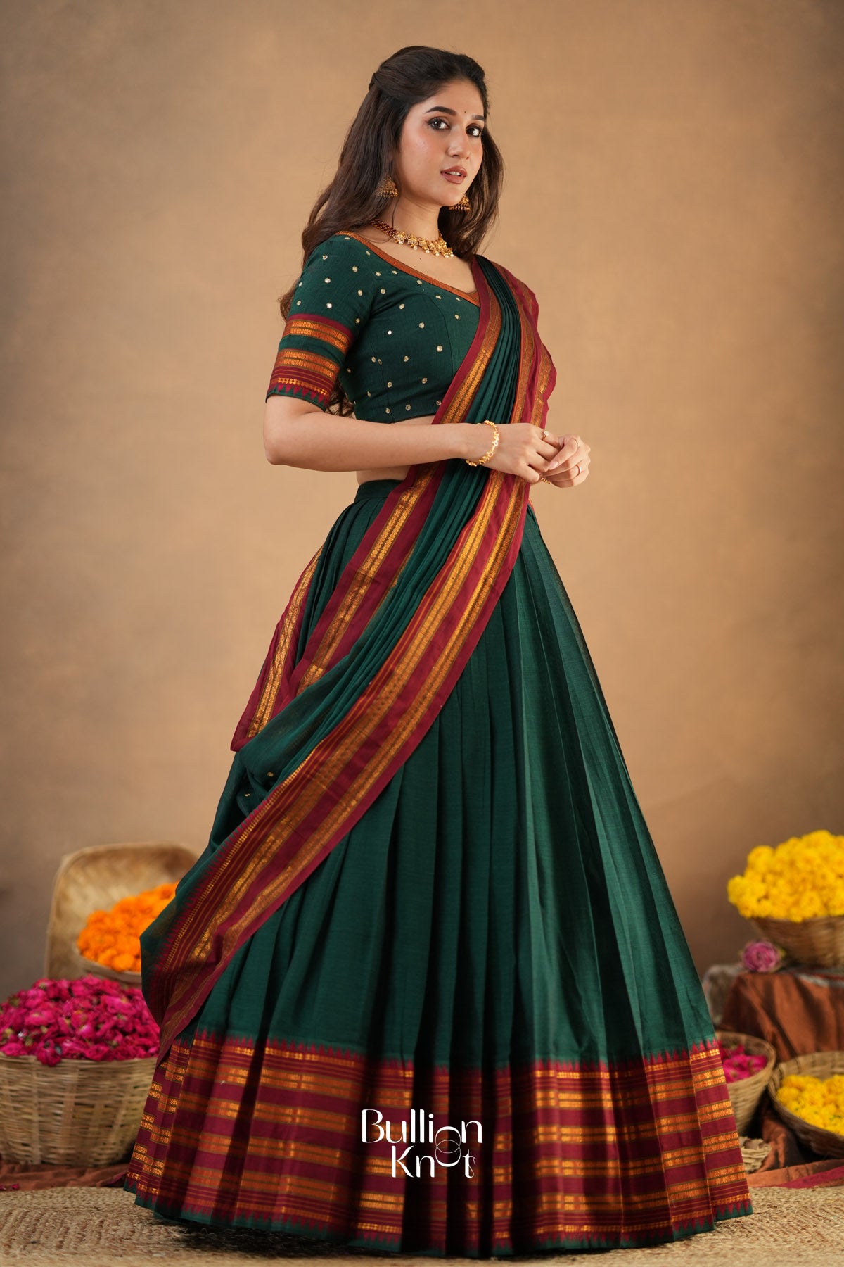 Woman wearing a green and red saree with a blurred background