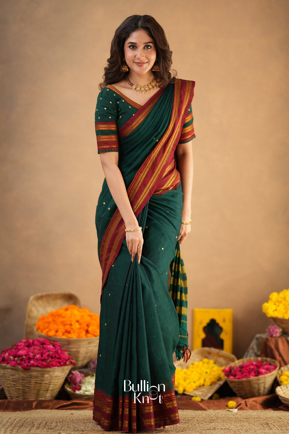 Woman in a green saree with a striped blouse standing