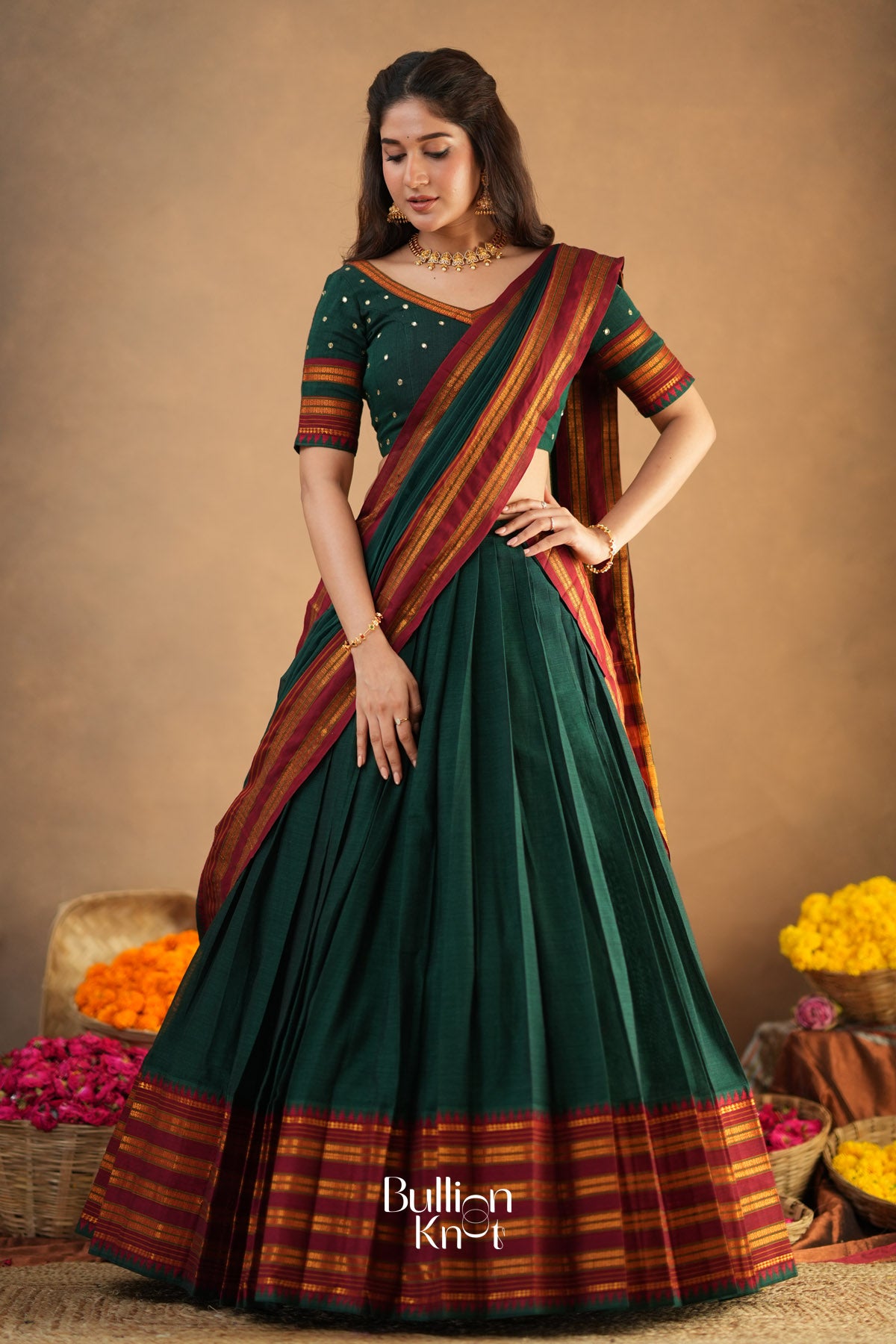 Woman wearing a green saree with red and gold border
