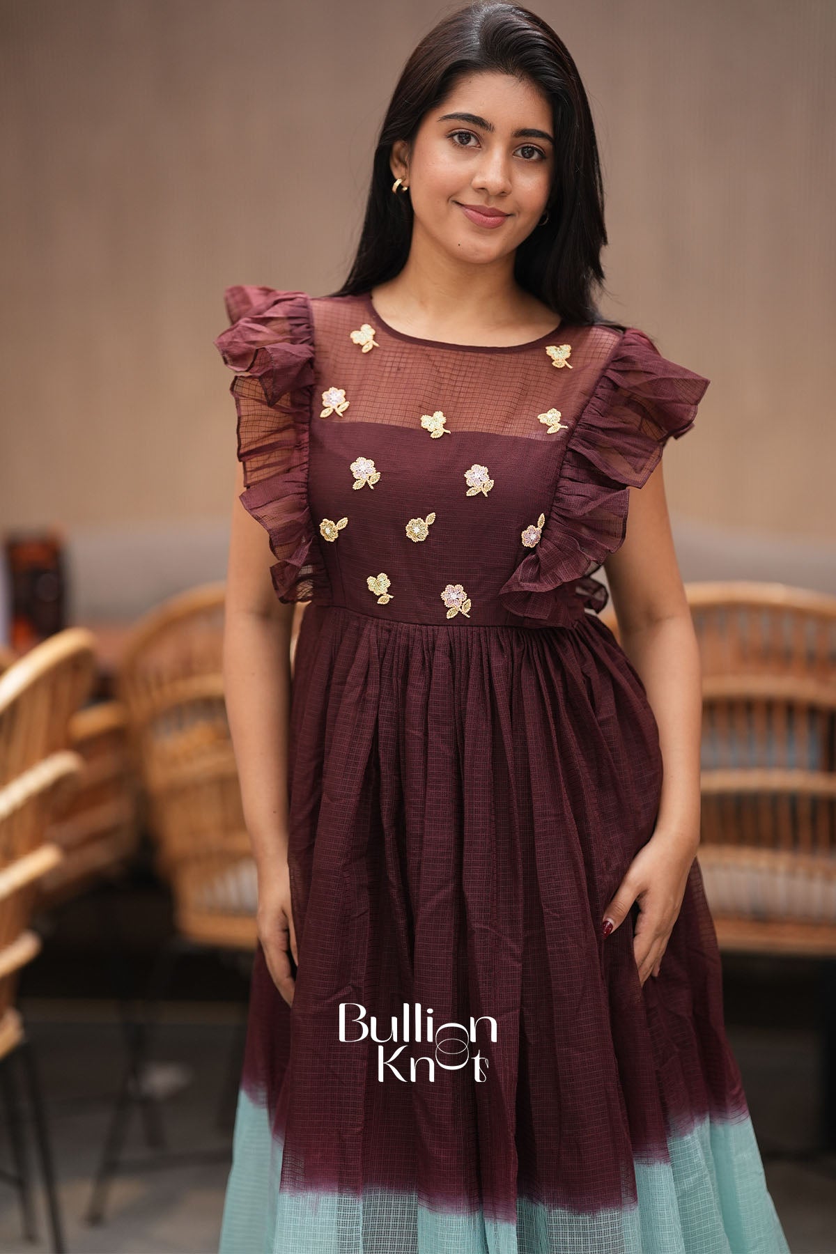 Woman wearing a maroon dress with floral embellishments