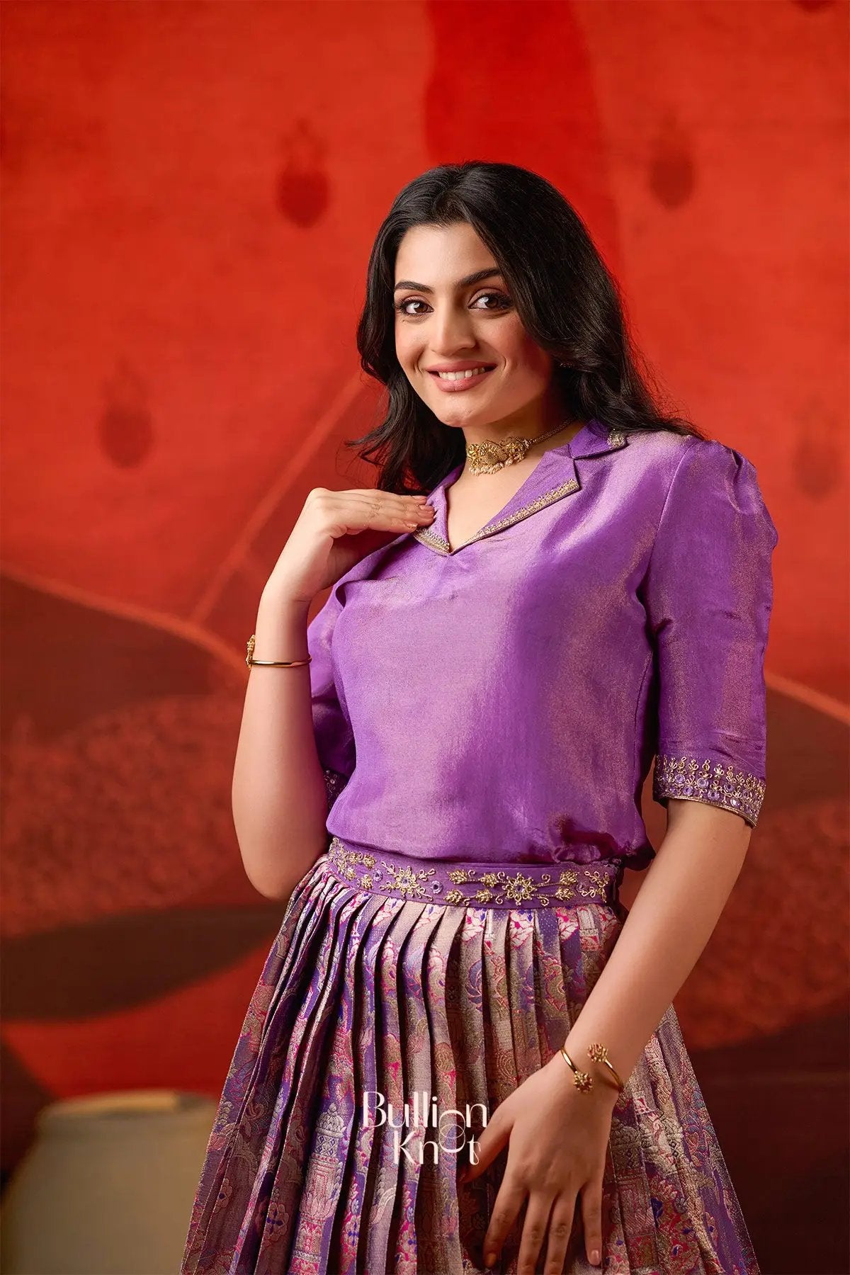 Model wearing Azaira Indo Western Lehenga in Red at bullionknot, showcasing elegant neckline and sleeve detailing on the purple blouse.