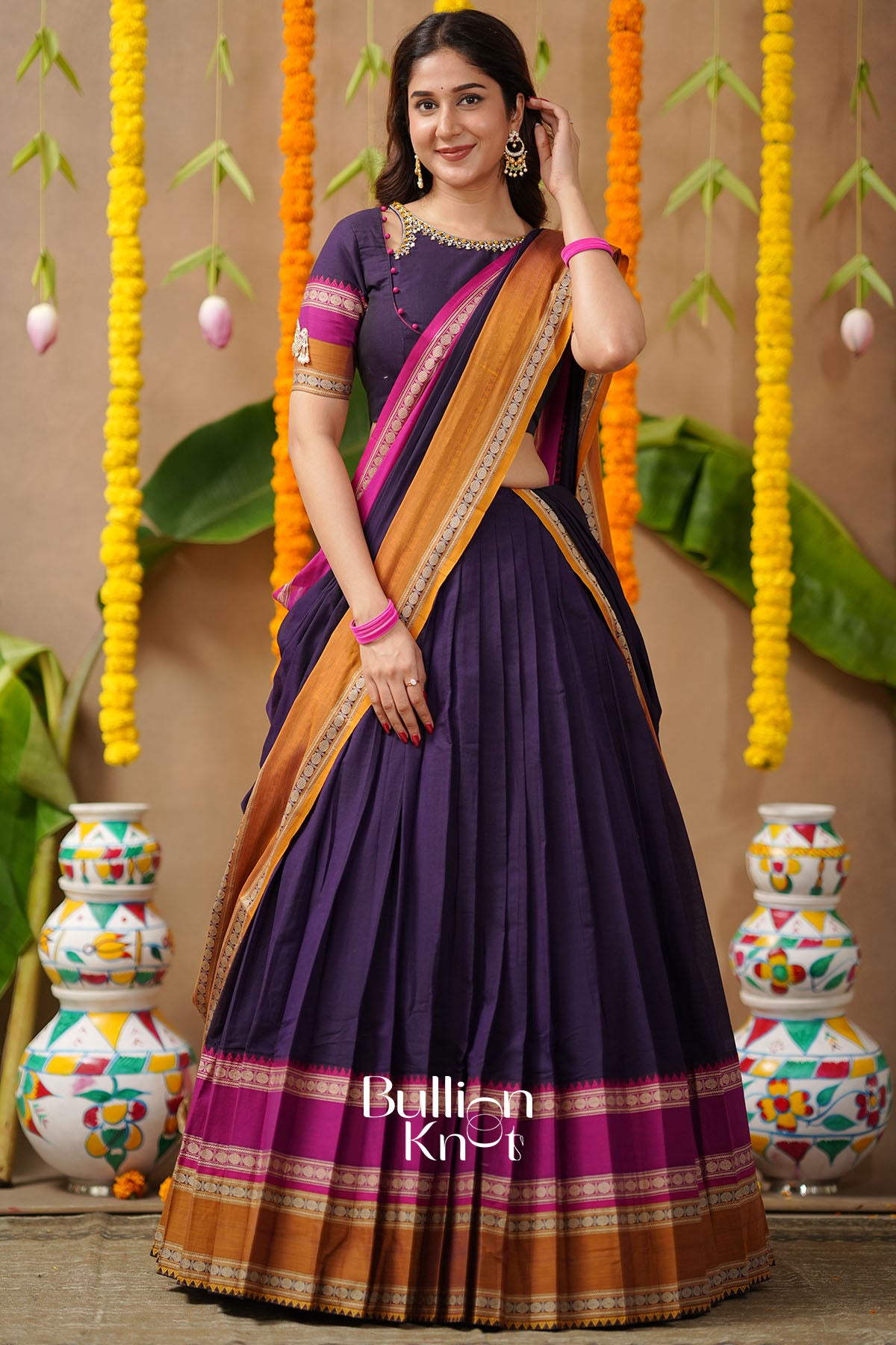 Woman wearing a purple saree with a brown border,