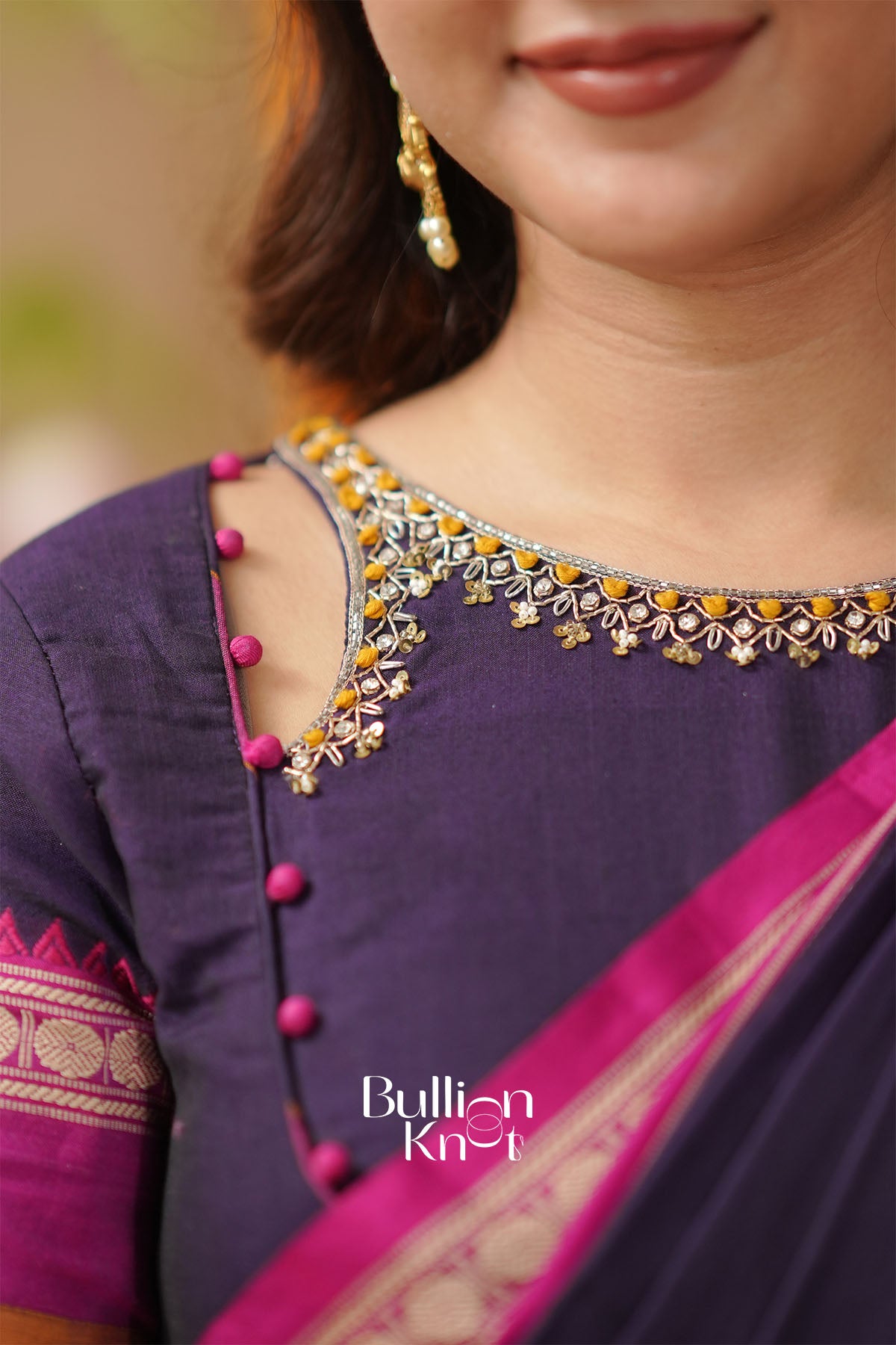 Purple saree with pink border and gold necklace,
