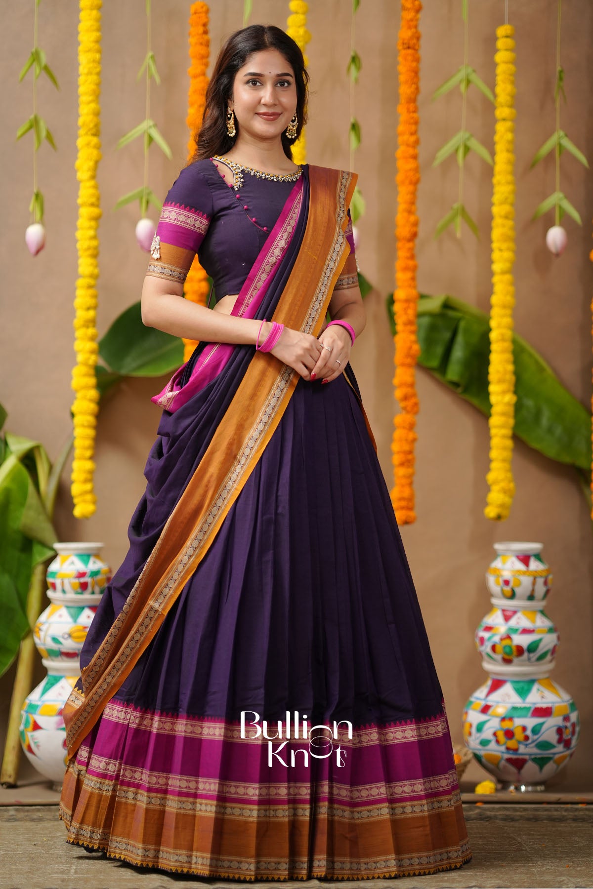 Woman in a purple saree with a brown border