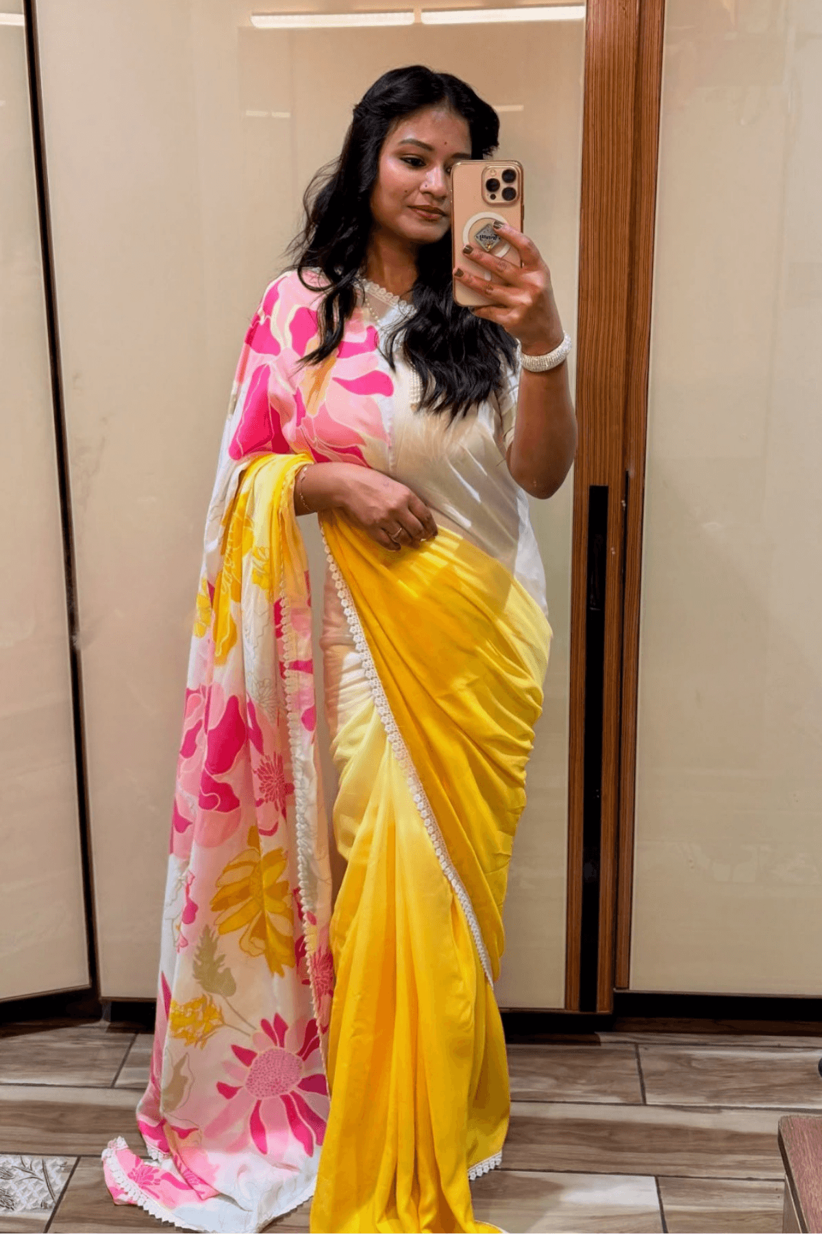 Woman wearing a yellow saree with pink floral patterns