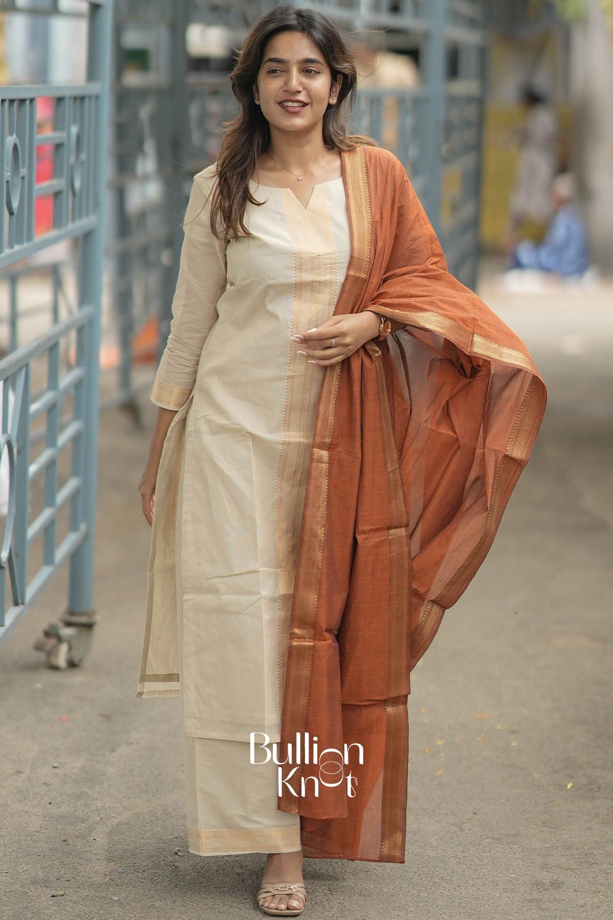 Woman in traditional beige and orange kurta set walking outdoors