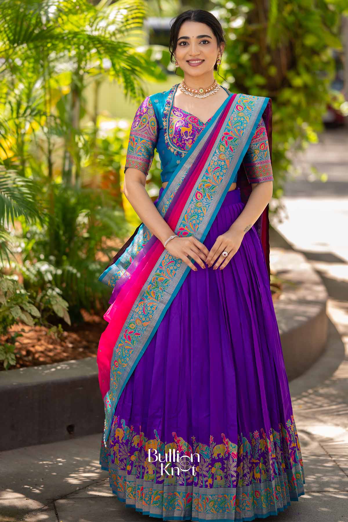 Elegant purple silk lehenga with colorful embroidered border, paired with a vibrant blue blouse with intricate embroidery, perfect for traditional occasions.