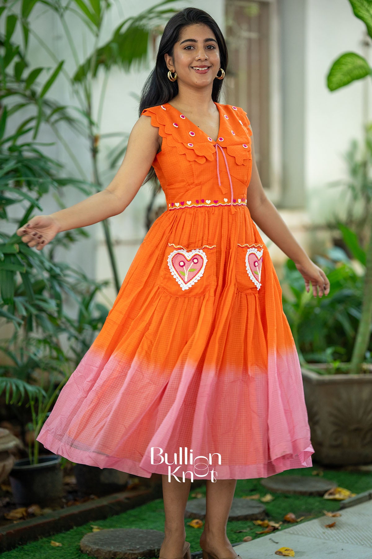 Woman wearing an orange and pink dress with heart designs