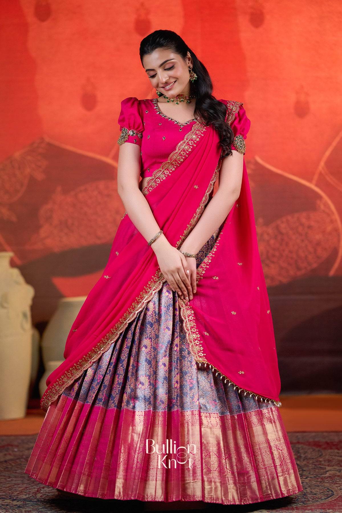 Model in Rithvika Banarasi Lehenga Set in Pink at bullionknot smiling in traditional attire with pleated skirt and embellished blouse.