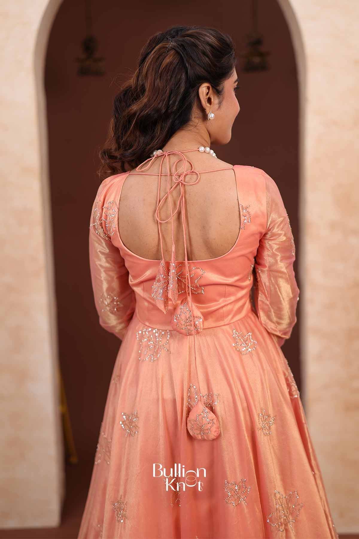 Close-up of model wearing pearl earrings and necklace, showcasing the embroidery and satin texture of the peach Indo Western Anarkali gown.