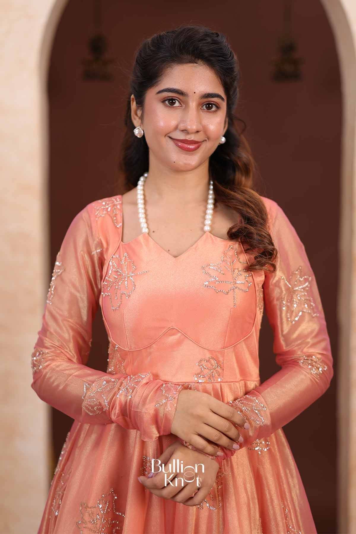 Back view of peach Indo Western Anarkali gown with tie-up back detail, embroidered floral motifs, and flowing satin fabric, model posing.
