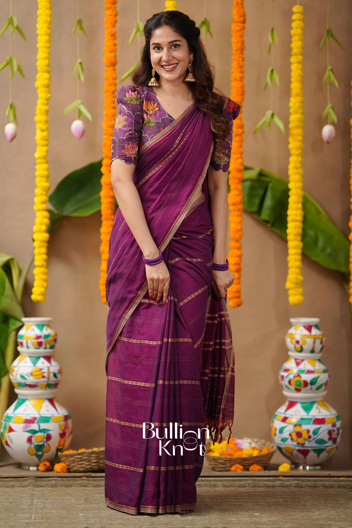 Woman in a purple saree with floral blouse standing in front