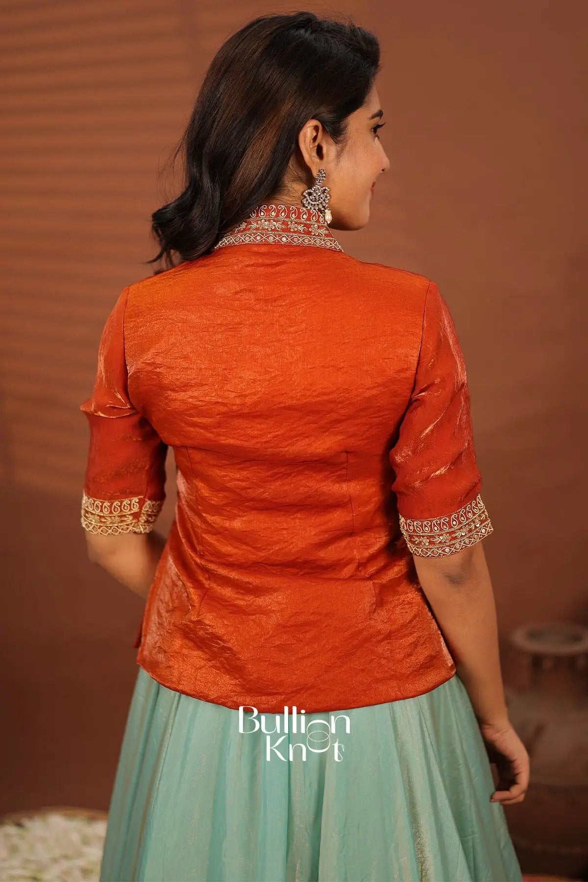 Back view of orange embroidered Indowestern jacket with pastel green skirt, traditional women's clothing