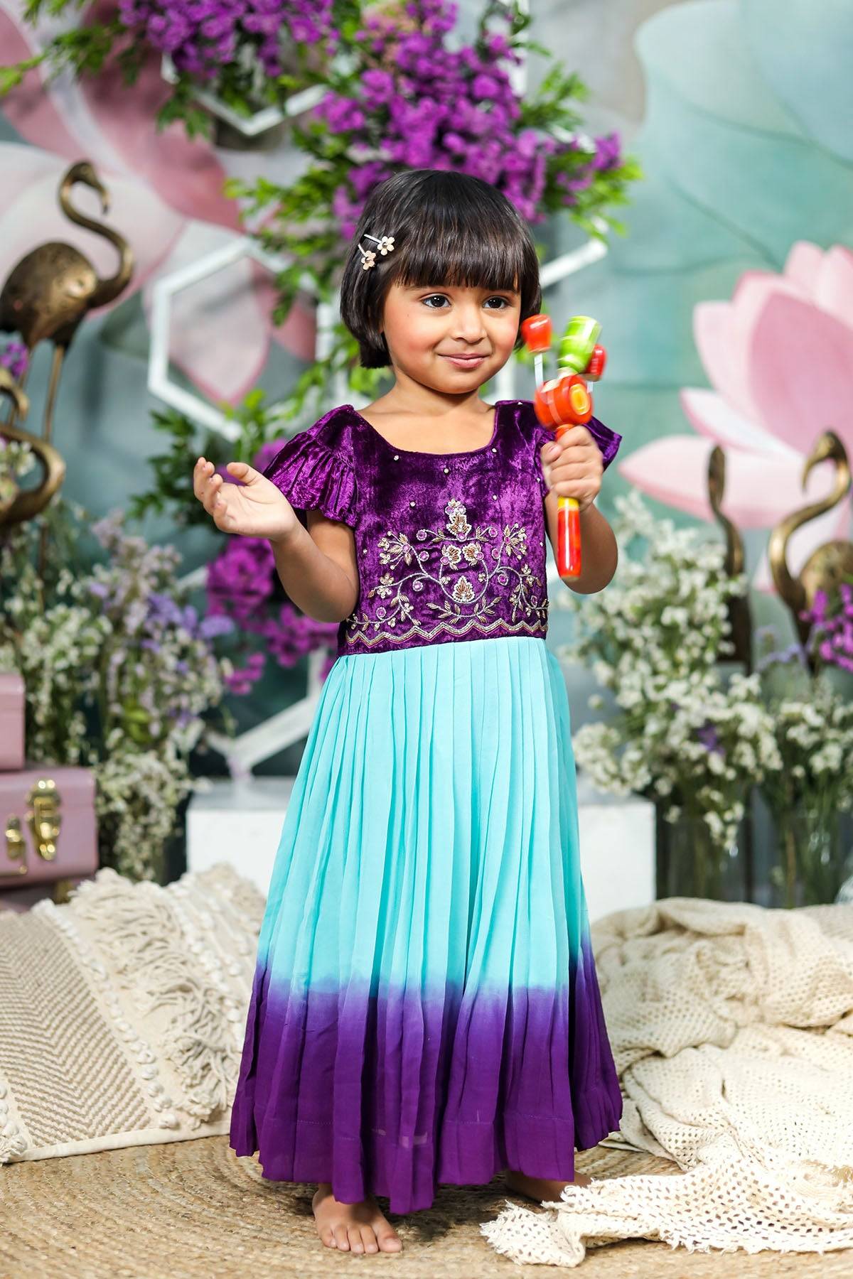 a little girl in a purple and blue dress