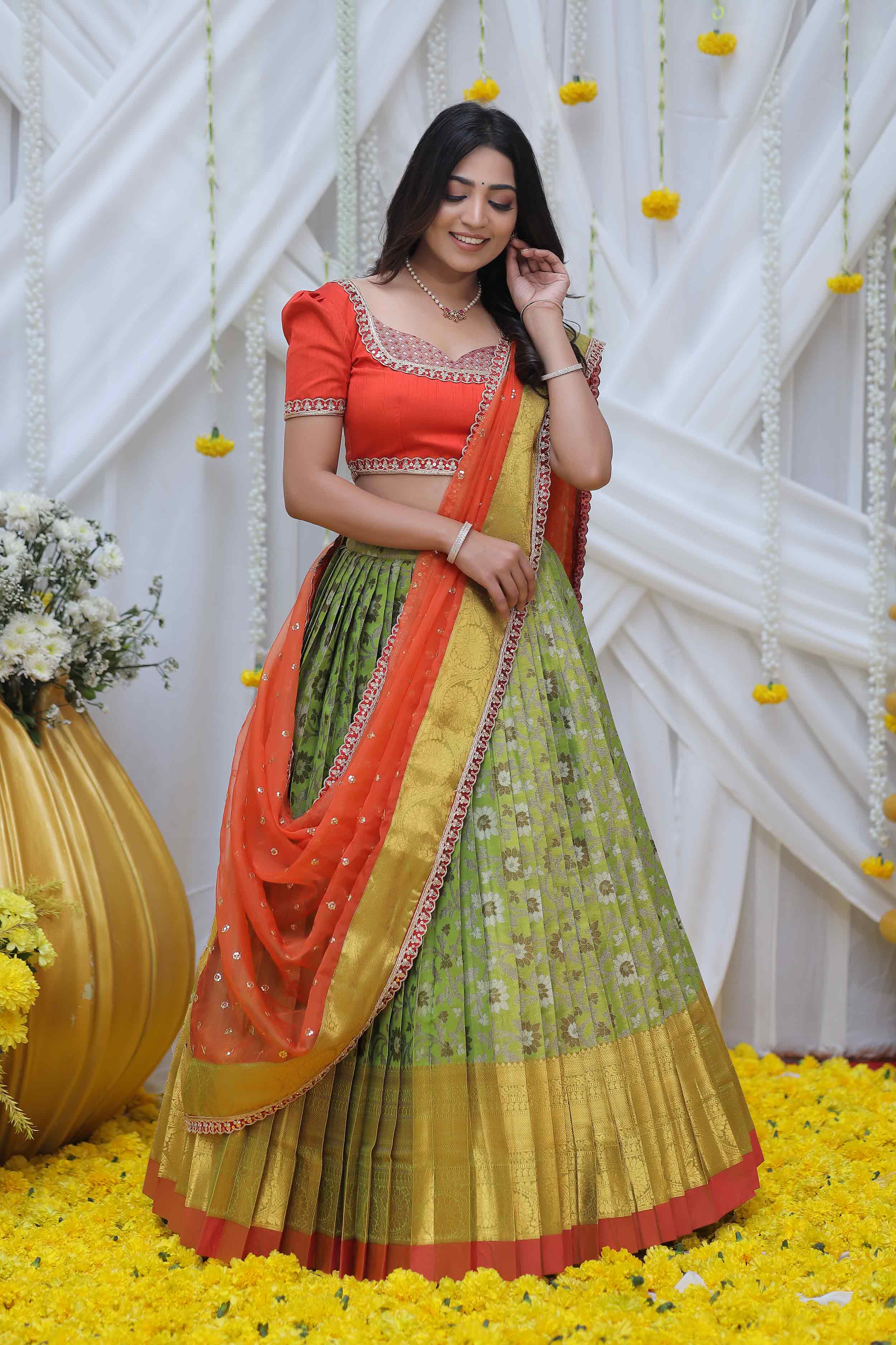 a woman in green and rust pattu half saree