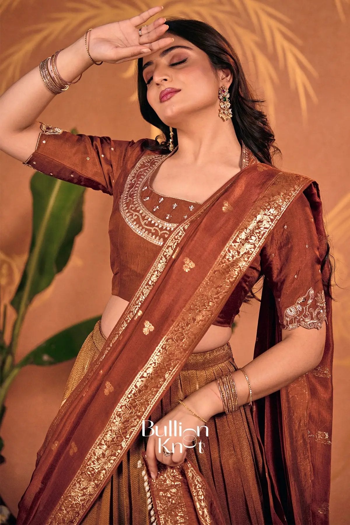 Woman in rust silk lehenga with detailed embroidery and jewelry