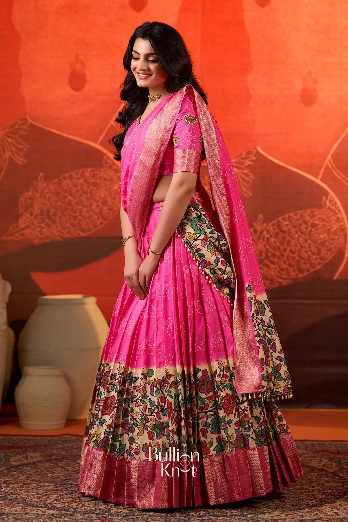 Side profile of Gokulika Lehenga Set In Pink at bullionknot highlighting the dupatta drape and vibrant floral lehenga design for festive attire.