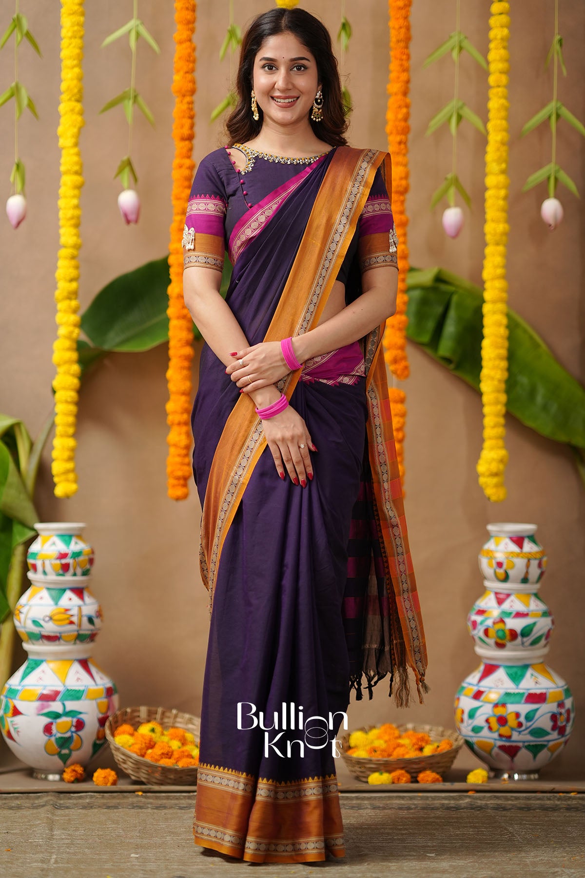 Woman in a purple saree with orange border 