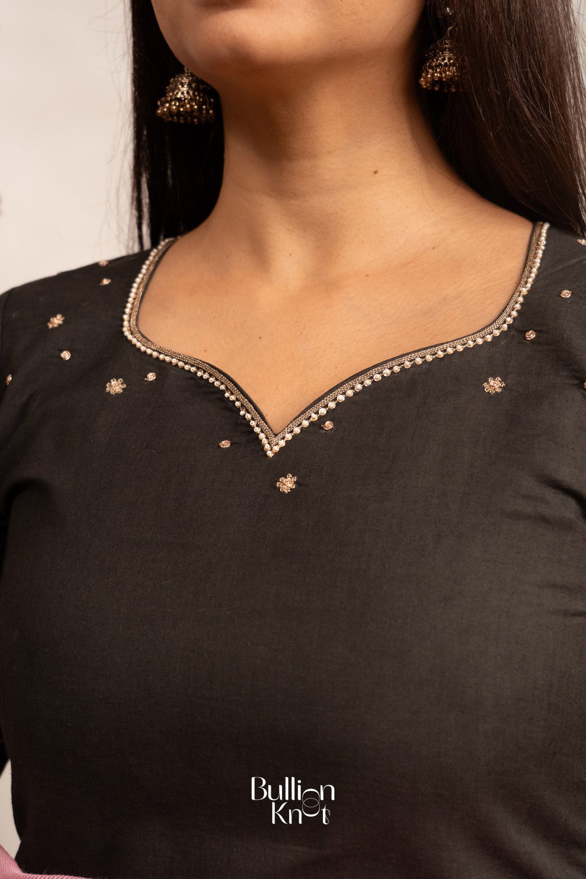 Black top with gold embroidery on a white background