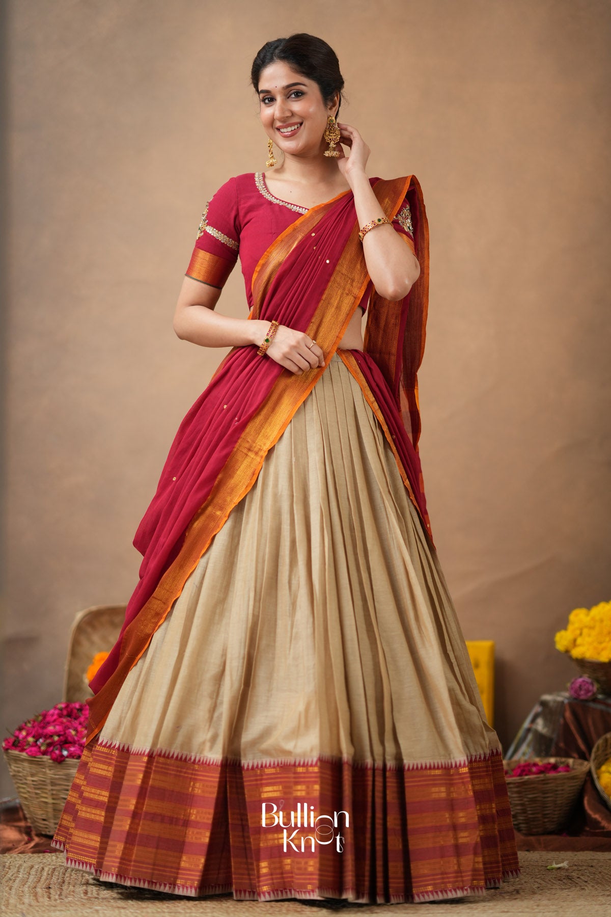 Woman wearing a traditional saree with a beige and red pattern against 