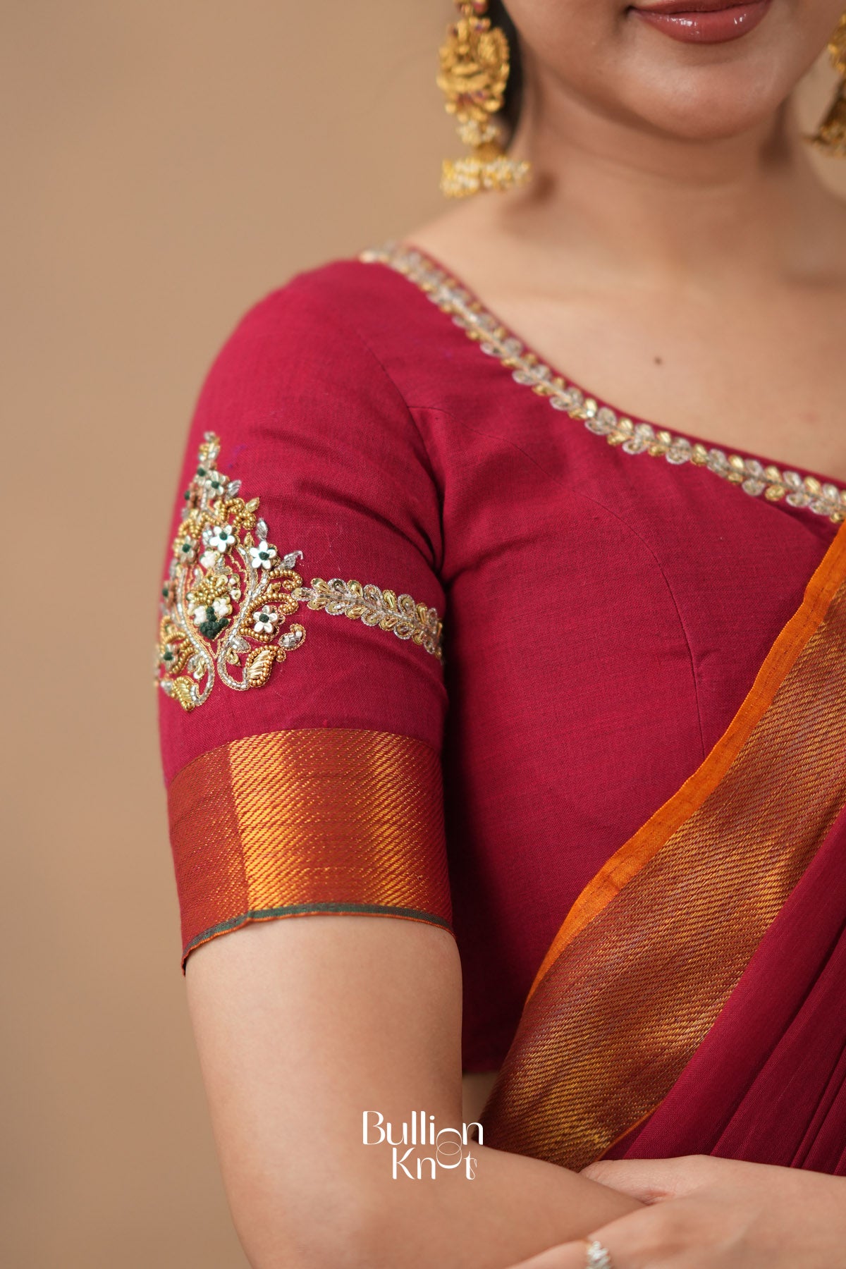 Close-up of a maroon saree with gold embroidery 