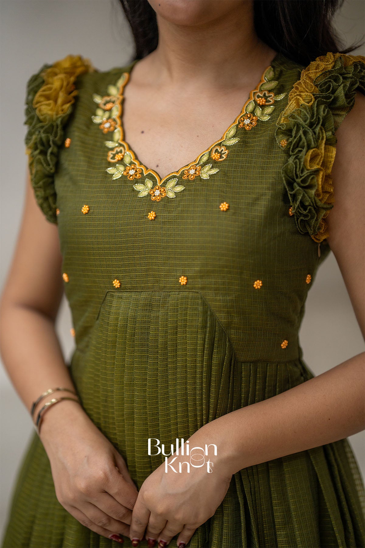 Green dress with floral embroidery and 'Bullion Knot' branding.