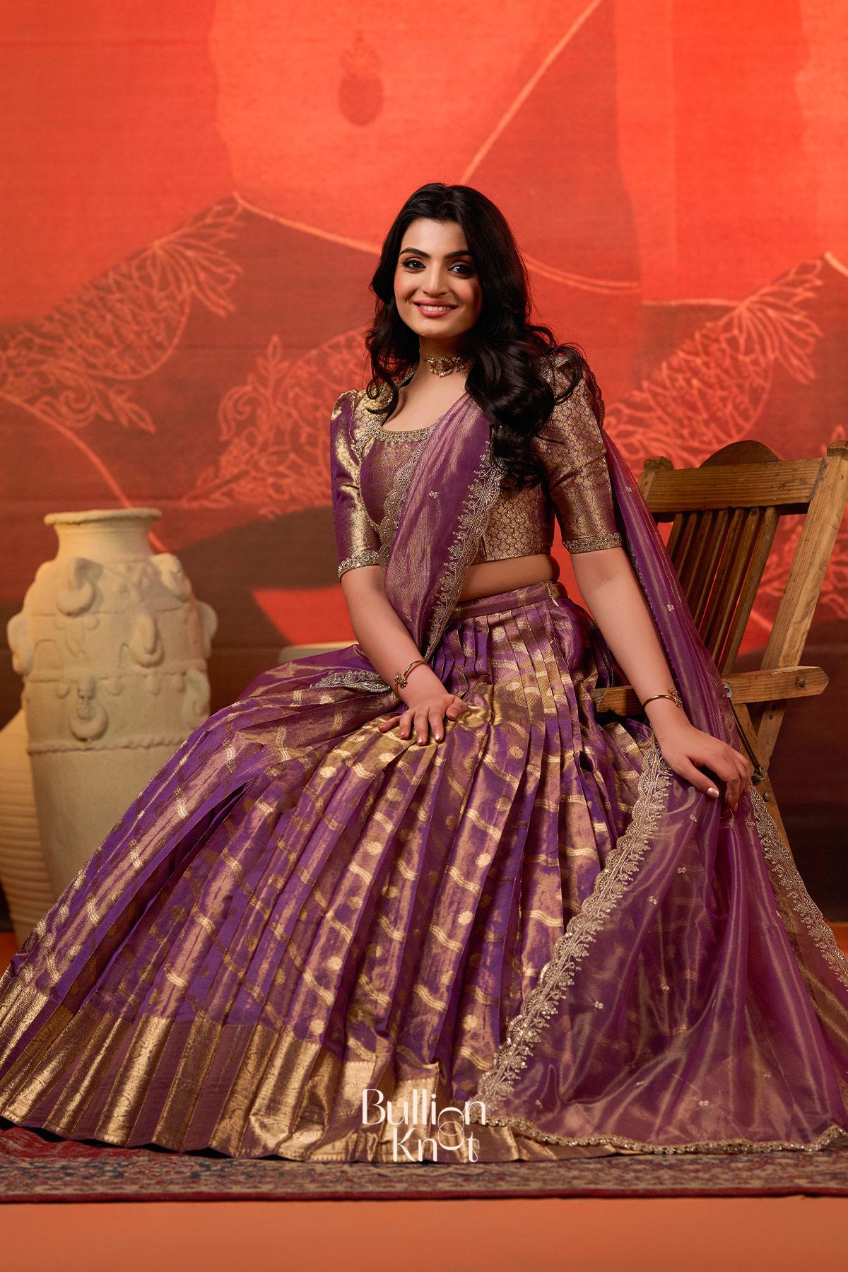 Close-up of purple lehenga with gold detailing, indoor background