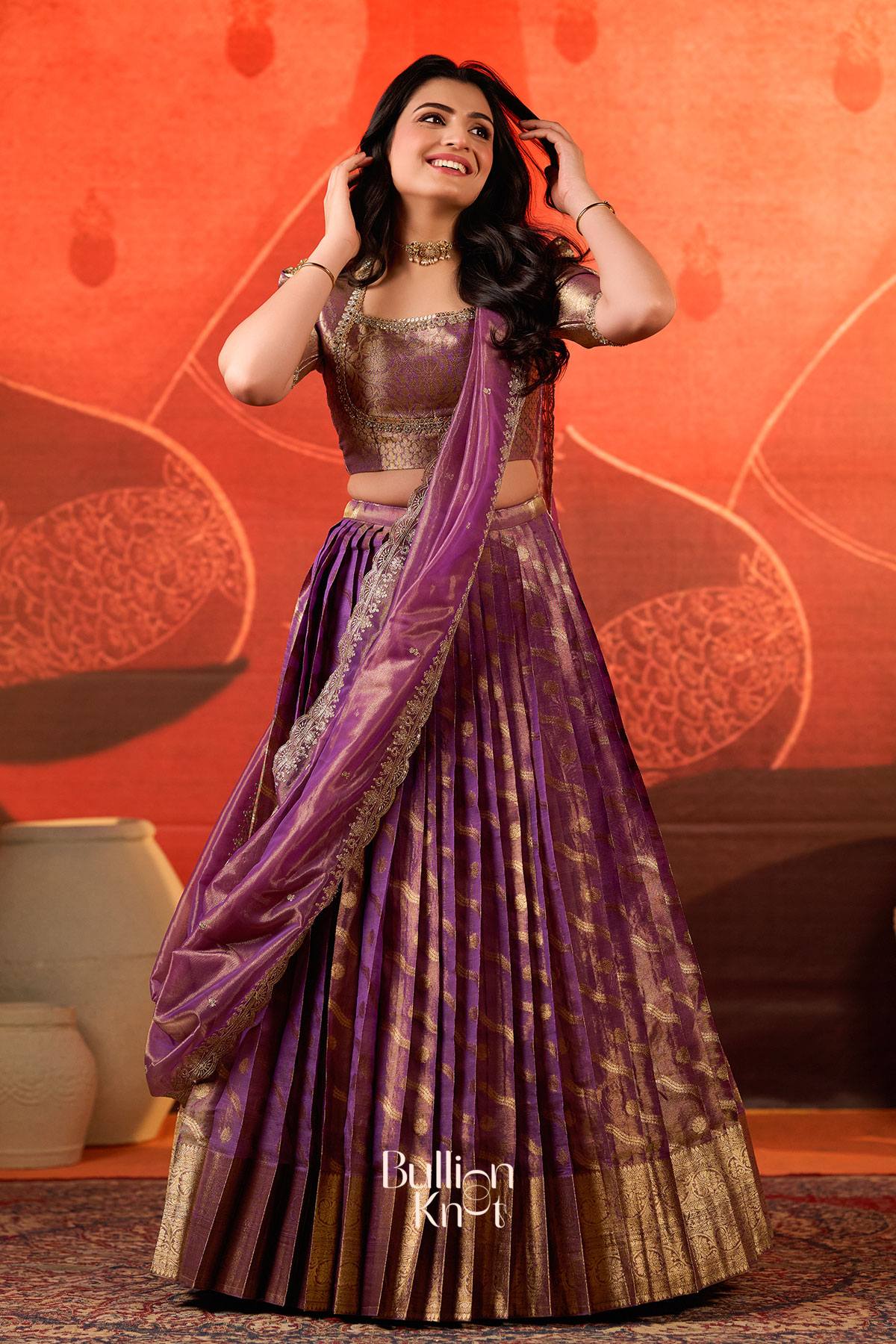 Women in traditional purple and gold lehenga, indoor setting